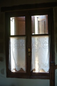 Stone walls, dark wood shutters, lace curtains - traditional Cretan window